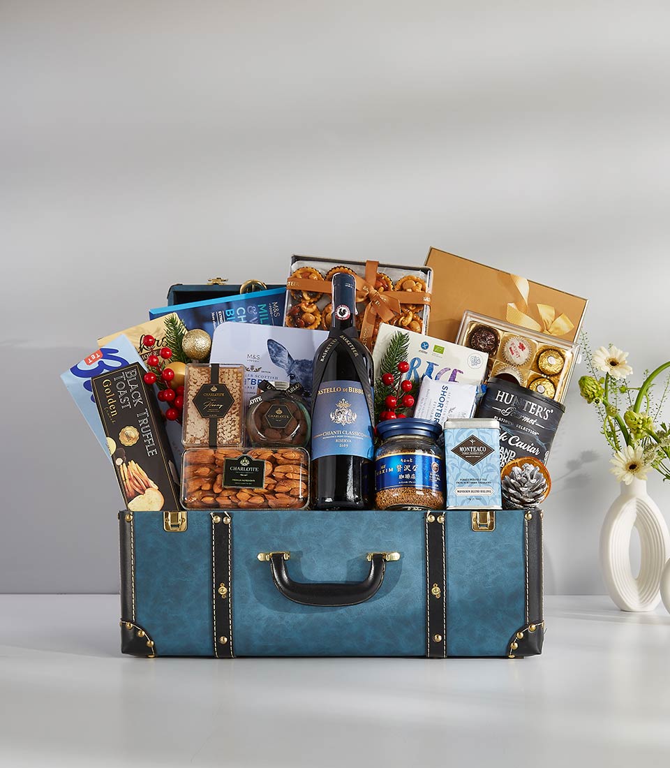 Luxury wine gift hamper in vintage blue trunk with red wine, gourmet snacks, and artisan chocolates