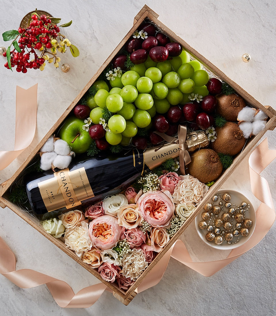 Chandon champagne gift hamper with fresh roses, grapes, apples, and kiwis in wooden crate with peach ribbon