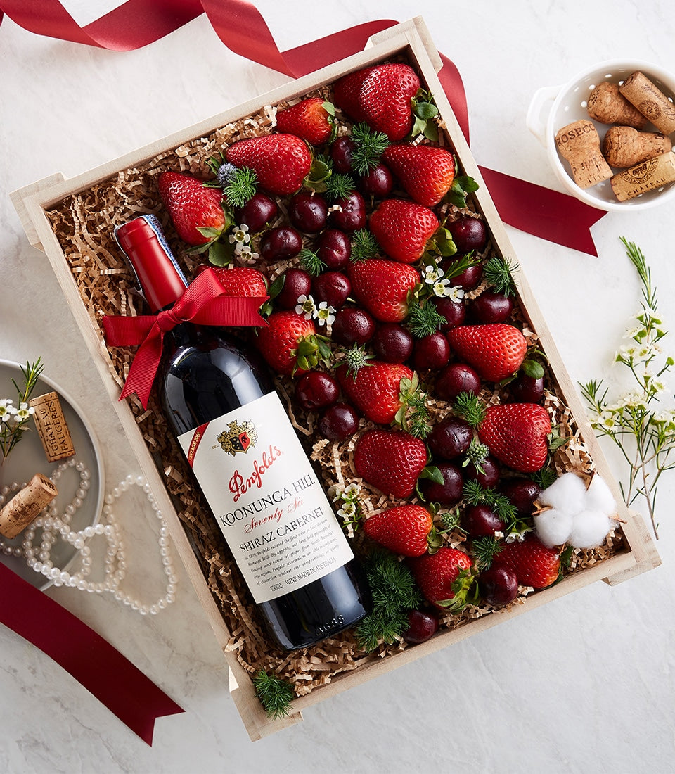 Classic red wine and fresh strawberries in wooden gift box with white flowers and red ribbon