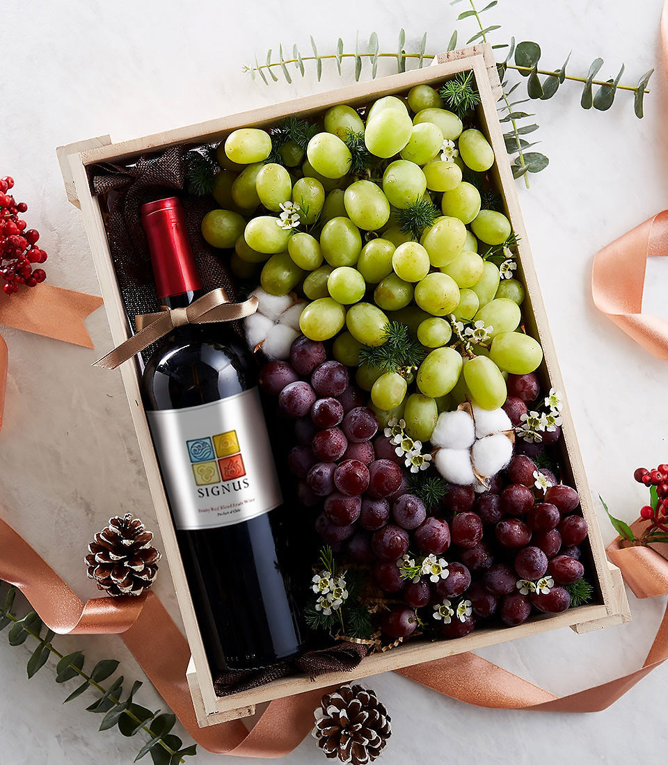 Luxury red wine and fresh grape gift box with white flowers and festive ribbon