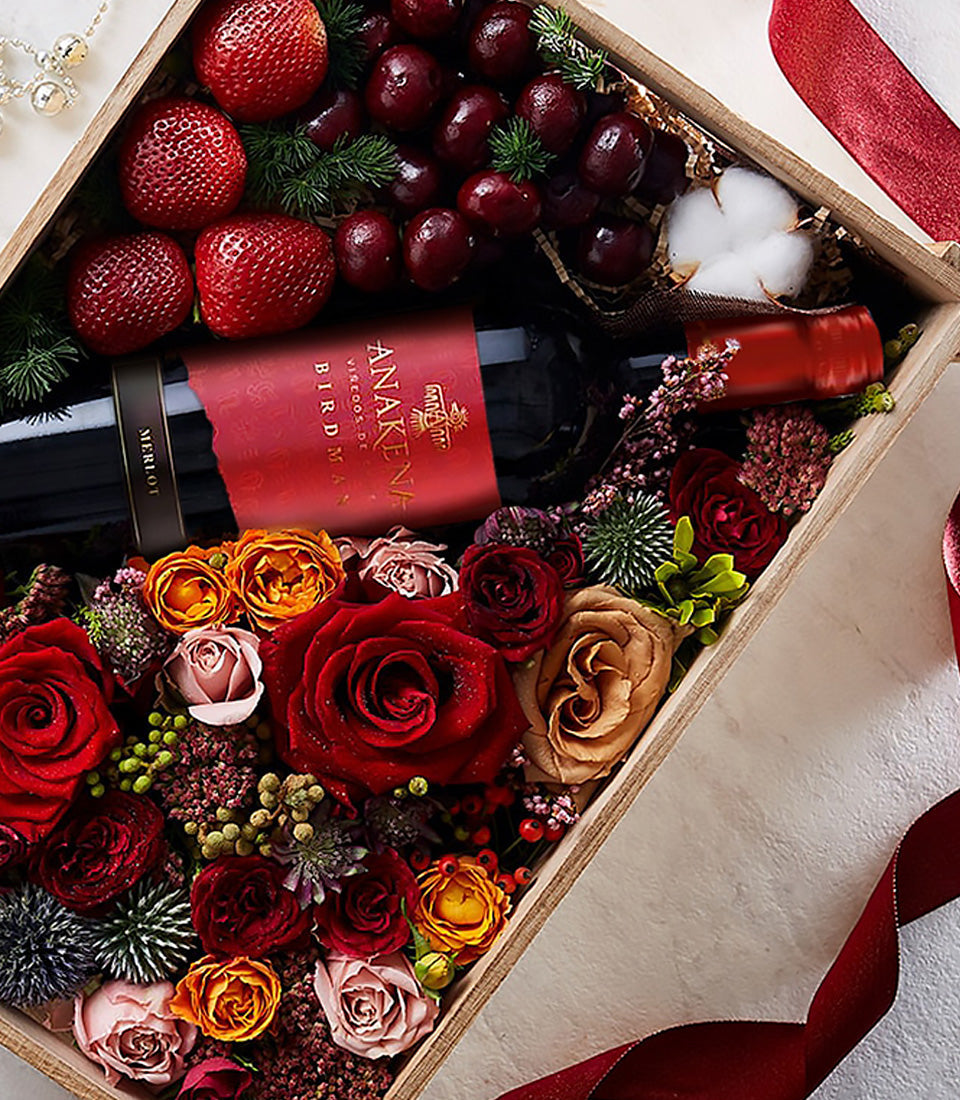 Luxury wooden gift box with red wine, fresh strawberries, cherries, and mixed roses in deep red, peach, and pink tones