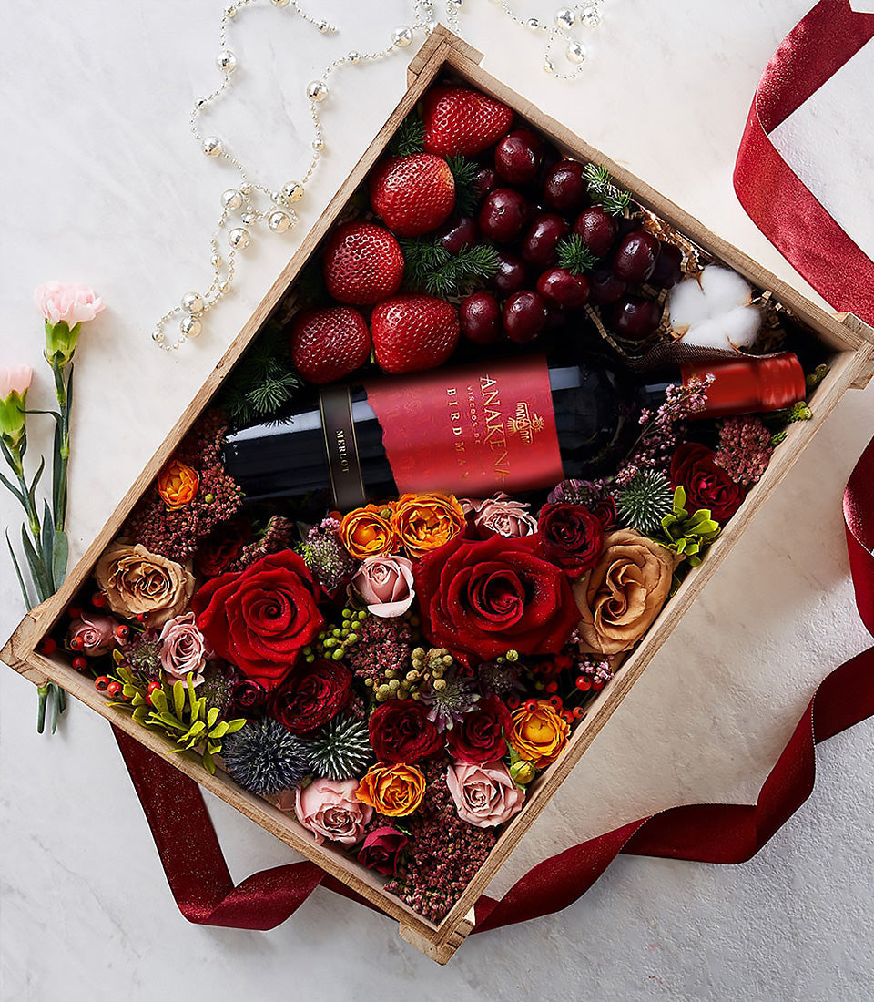 Premium red wine gift box with Merlot, fresh berries, and romantic red roses in wooden hamper