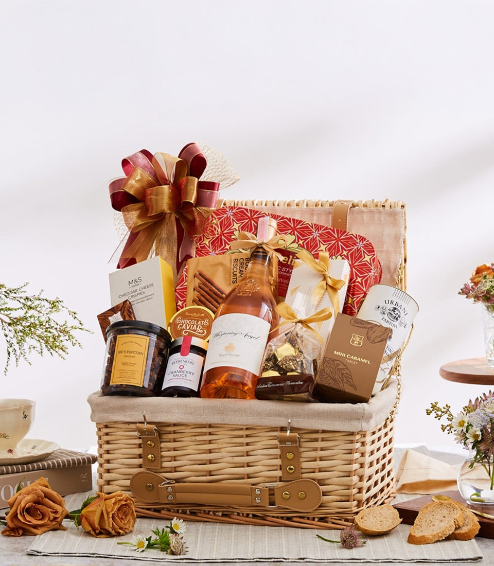 Premium rosé wine and gourmet gift hamper in woven wicker basket with artisan chocolates, crackers, and caramel treats