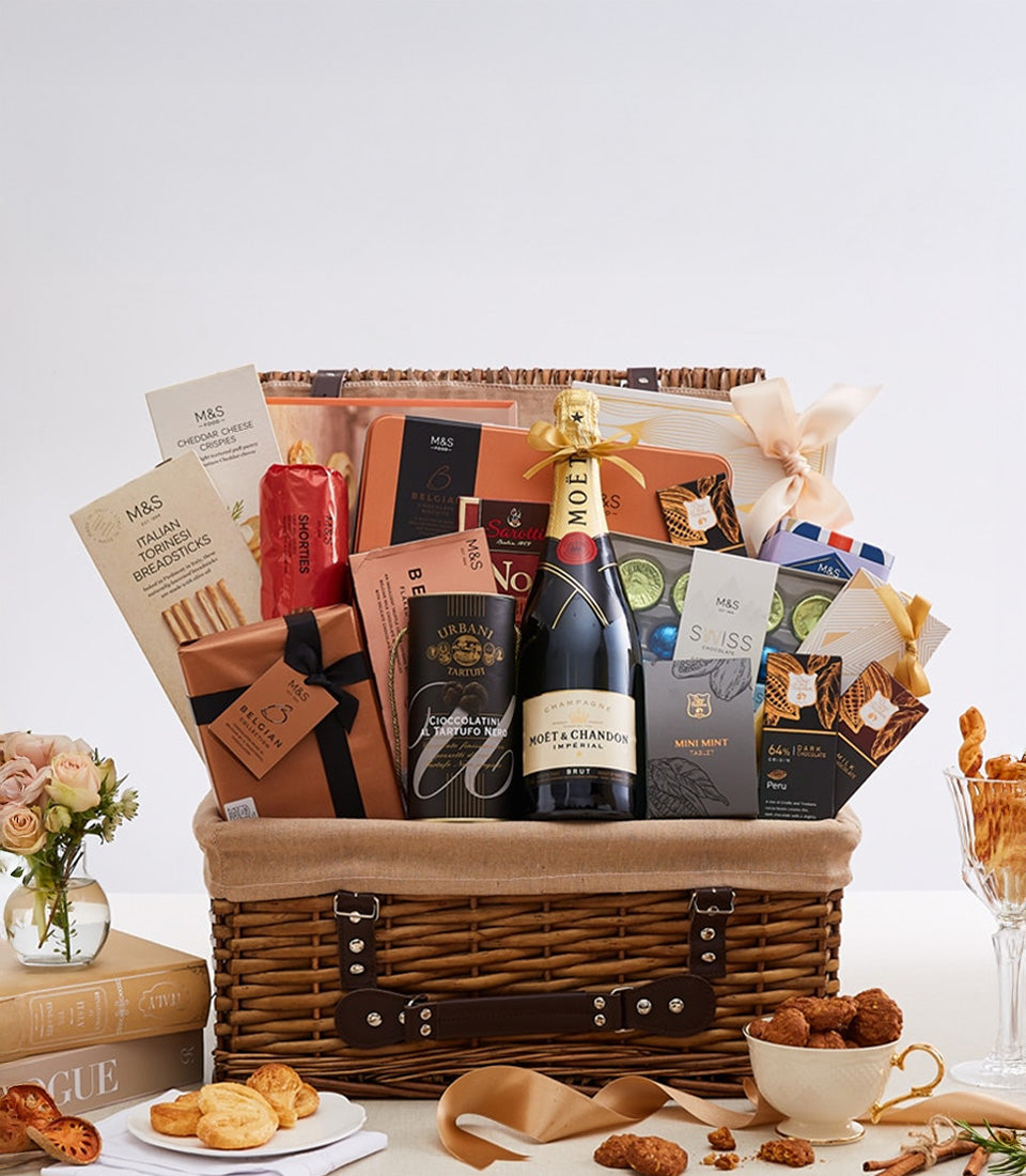 Woven wicker hamper with champagne, gourmet chocolates, cheese crisps, and artisan provisions in gold and brown packaging