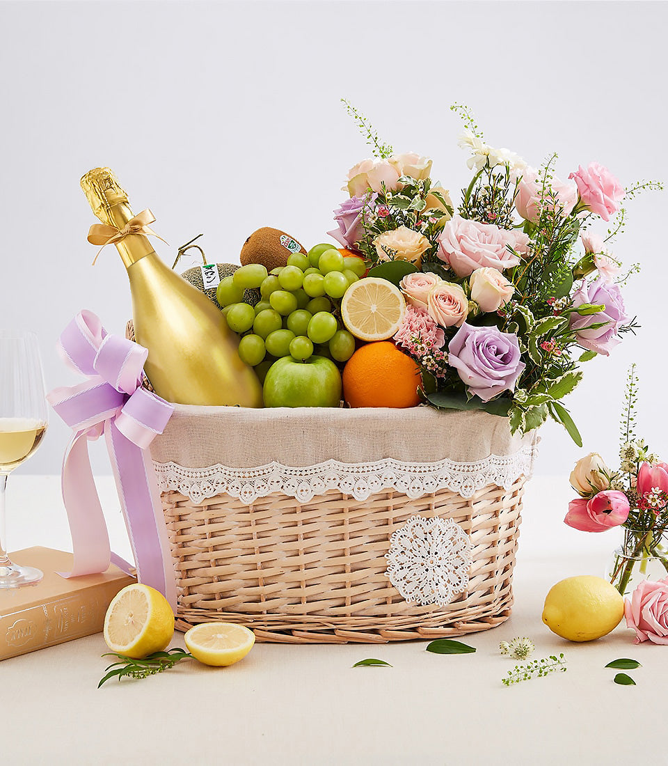 Luxury golden champagne, fresh pastel roses, and seasonal fruit gift basket for anniversaries