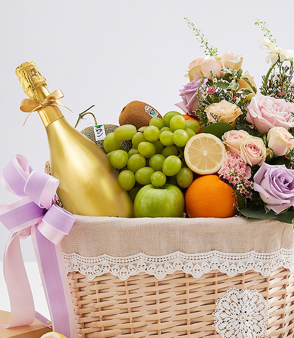 Luxury wicker gift basket with gold sparkling wine, fresh fruits, and pastel rose bouquet for anniversary celebrations