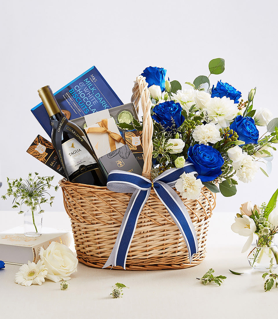 Premium wine gift basket with blue roses, white dahlias, and gourmet snacks