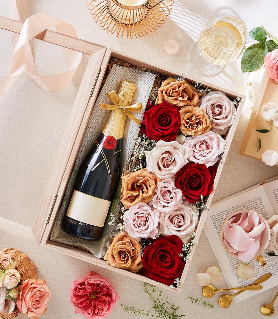 Luxury champagne bottle with red and blush roses in wooden gift box, perfect for Valentine's Day