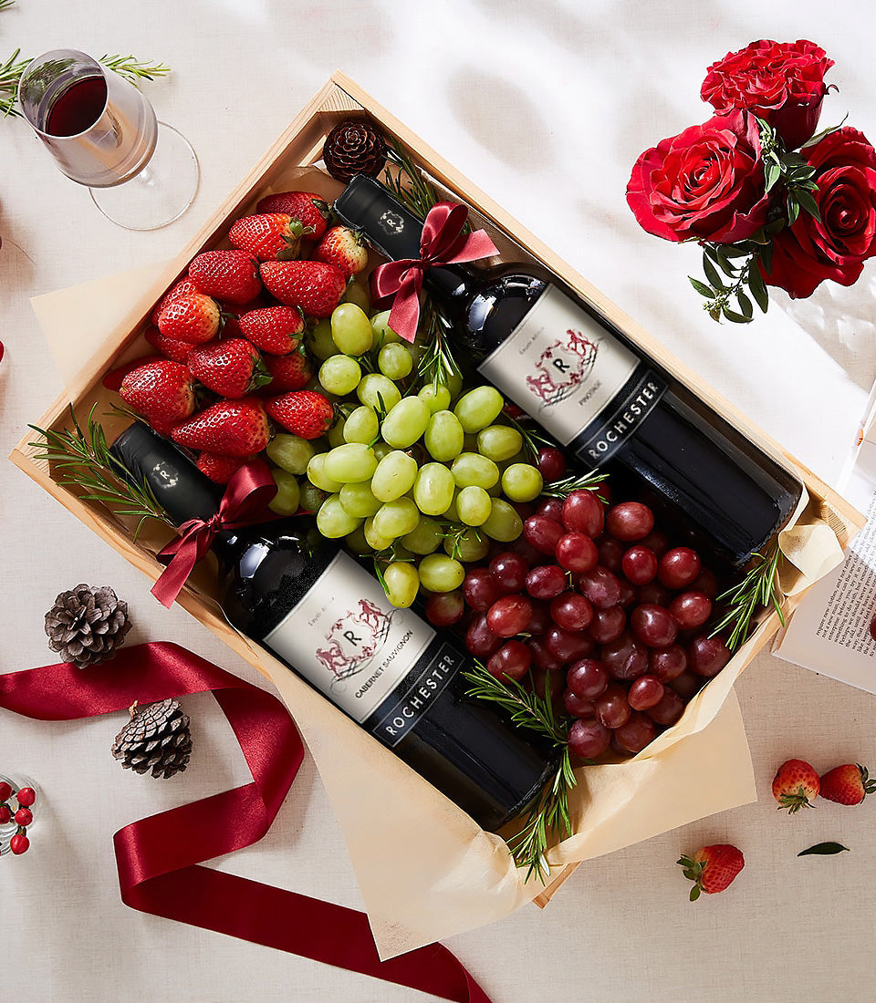 Wooden gift box with Rochester Pinot Noir and Cabernet Sauvignon, fresh grapes, strawberries, and rosemary