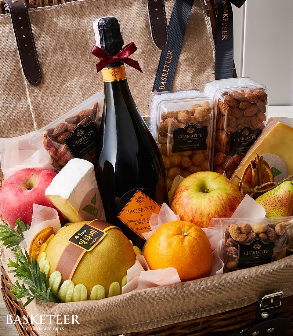Woven wicker luxury gift hamper with Prosecco, brie cheese, fresh fruit and gourmet nuts