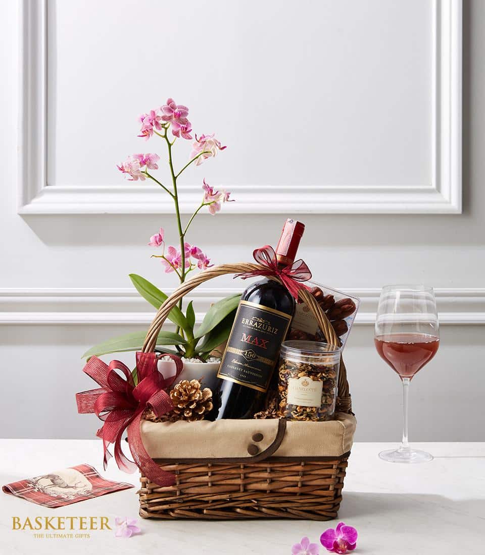 Premium red wine gift basket with pink orchid, pecans, and gourmet treats in wicker
