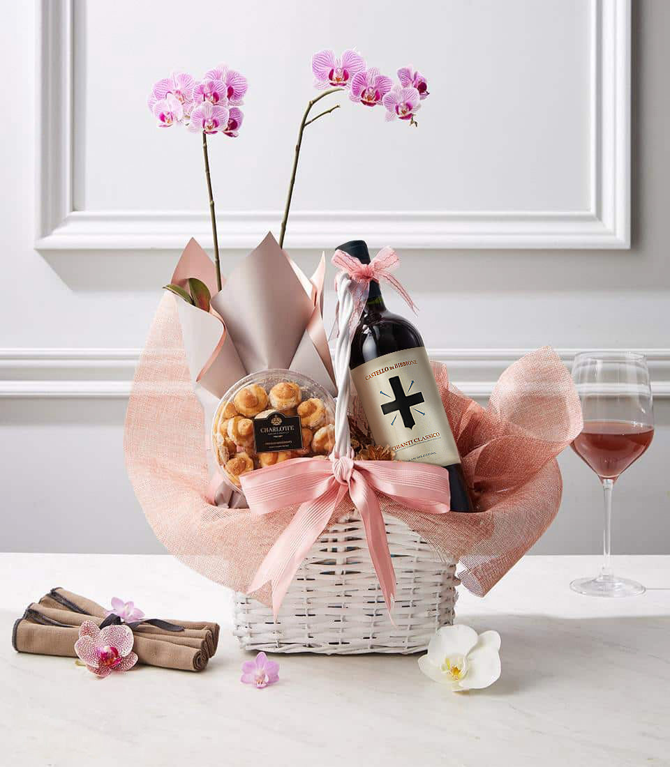 Luxury wine gift basket with pink orchids, red wine, and artisan baked goods