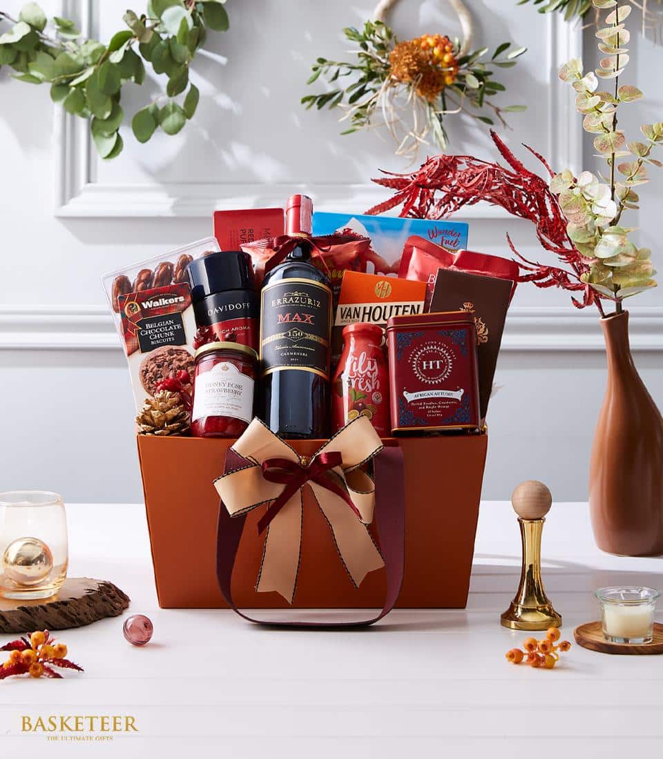 Premium wine gift basket with gourmet chocolates, tea, and jam in deep burgundy tones