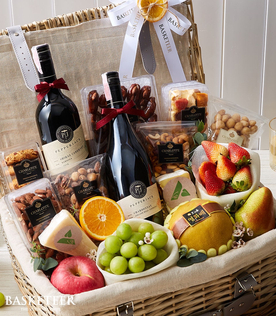 Premium wine and gourmet fruit hamper with Shiraz, Chardonnay, fresh strawberries, grapes, nuts, and artisan snacks in woven