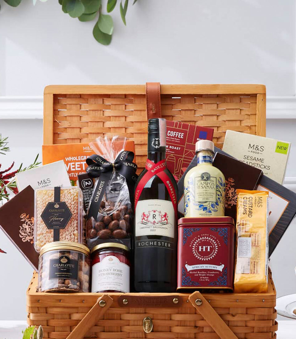 Premium red wine gourmet gift hamper in woven wicker basket with olive oil, artisan foods, and honey spread