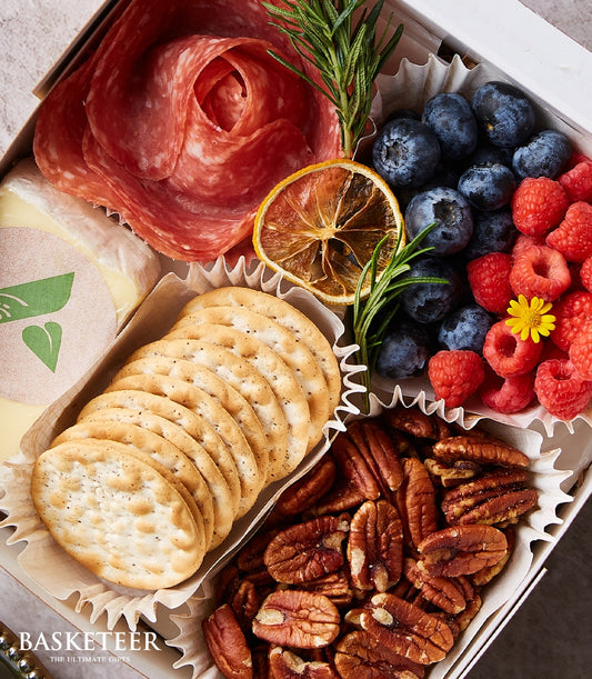 Gourmet mini charcuterie box with salami rose, brie cheese, berries, crackers and pecans in white-lined compartments
