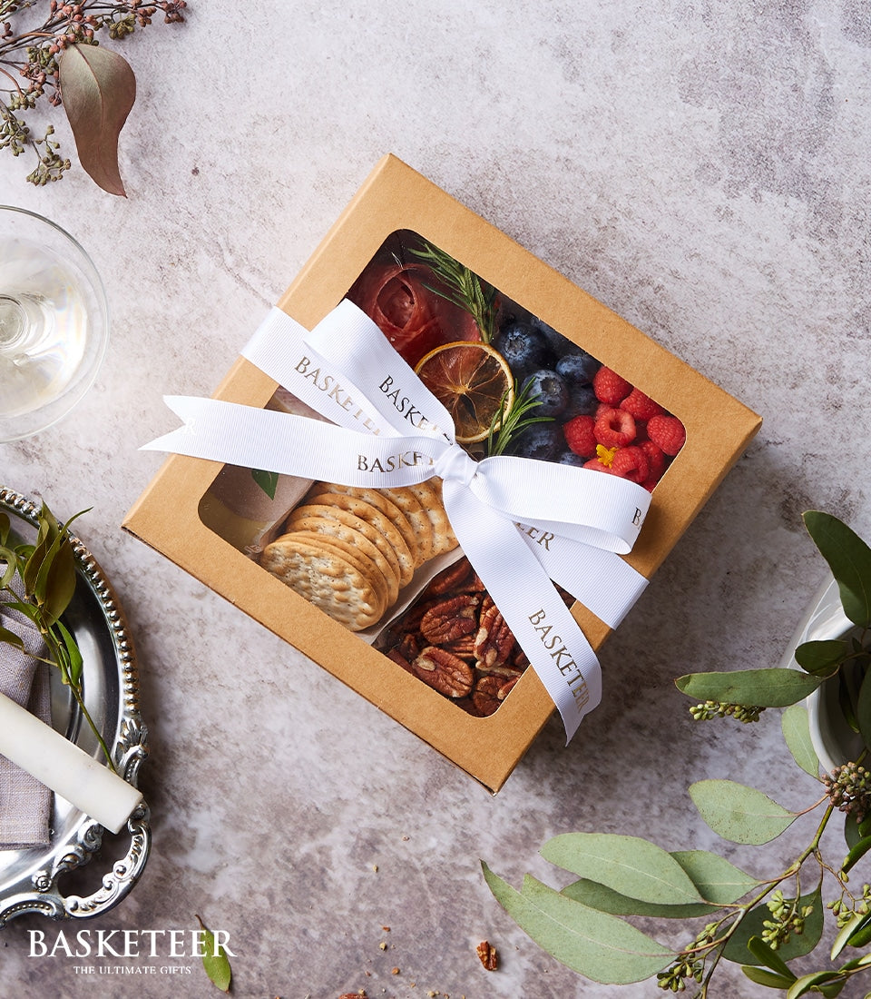 Gourmet mini charcuterie box with cured meats, berries, crackers, and pecans in luxury gift packaging