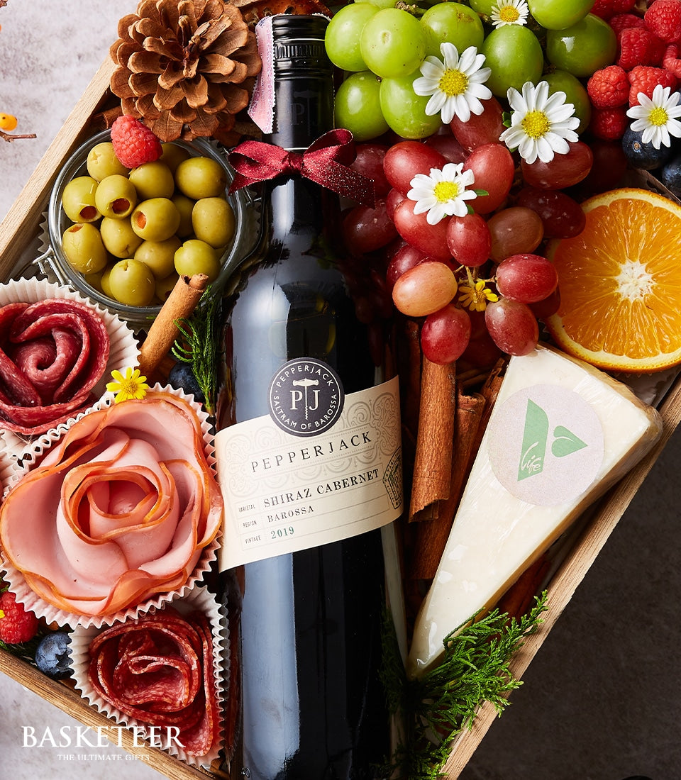 Premium wine and charcuterie gift box with Shiraz Cabernet, artisan cheese, cured meats, and fresh grapes in wooden tray