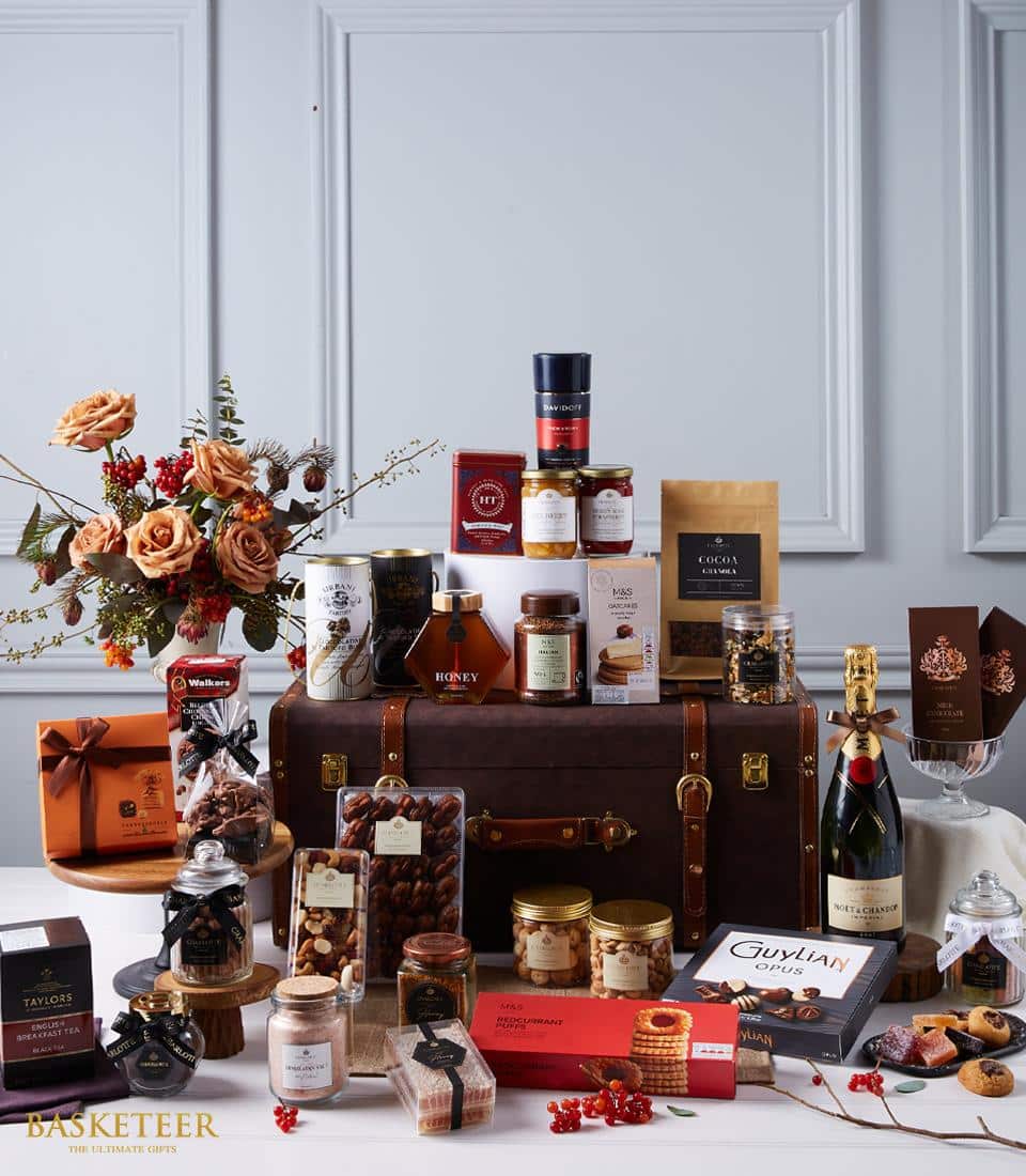 Luxury champagne and gourmet gift hamper with peach roses, chocolates, and artisan treats in brown leather trunk