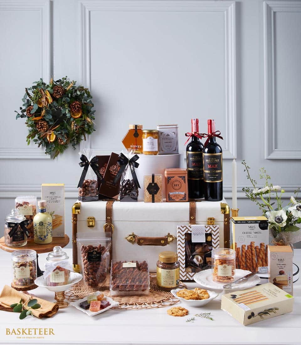 Luxury red wine and gourmet hamper with artisan chocolates, preserves, and gourmet snacks in leather-strapped trunk