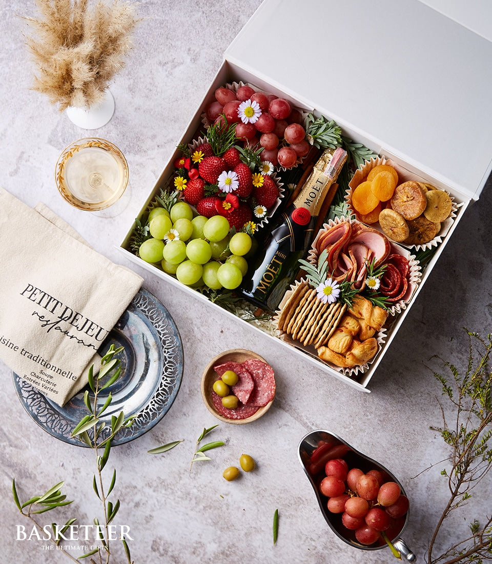 Luxury champagne and charcuterie gift box with fresh grapes, strawberries, dried fruit, Moët & Chandon, cured meats, and