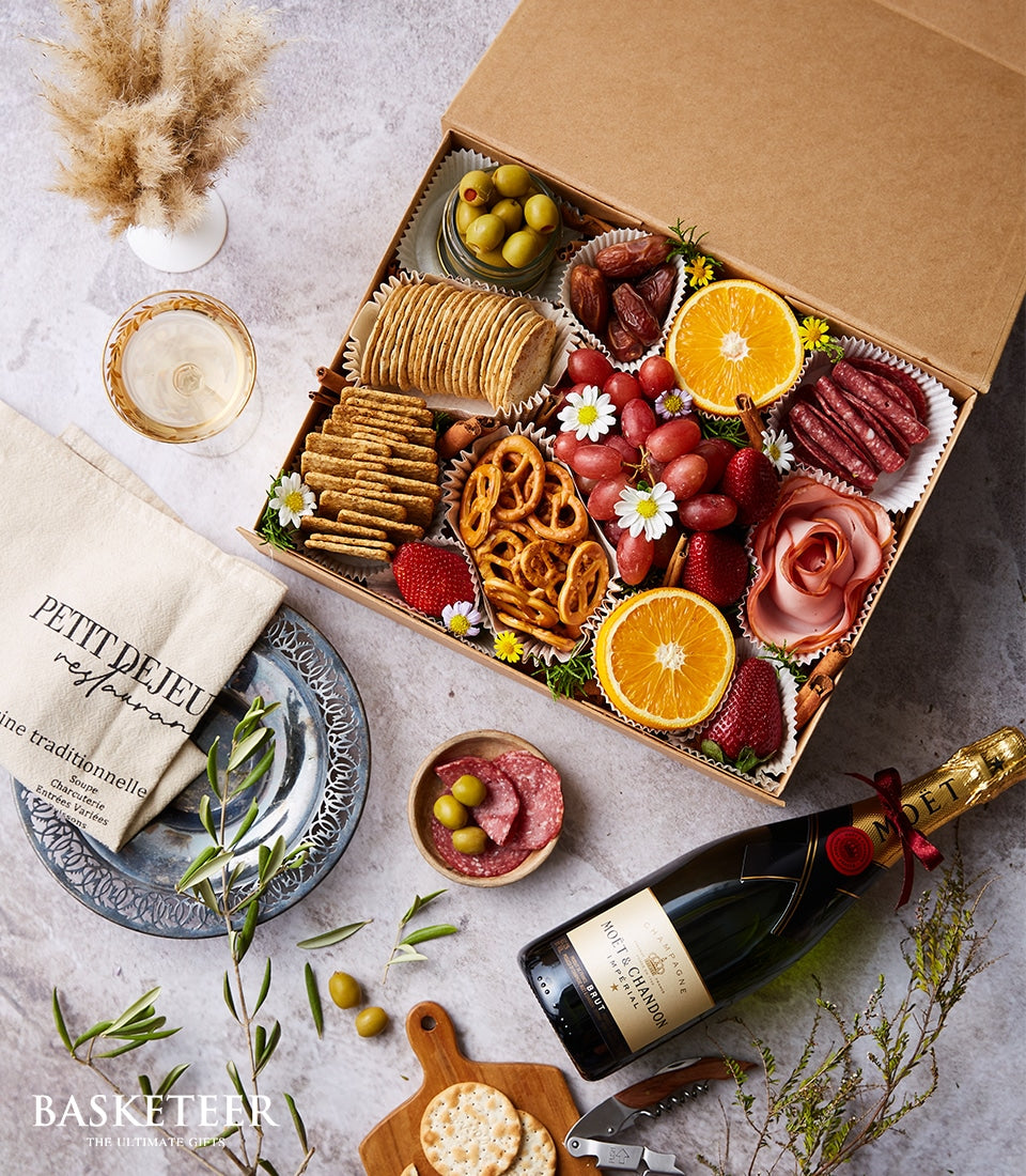 Luxury charcuterie and champagne gift box with gourmet crackers, cured meats, and fresh fruit