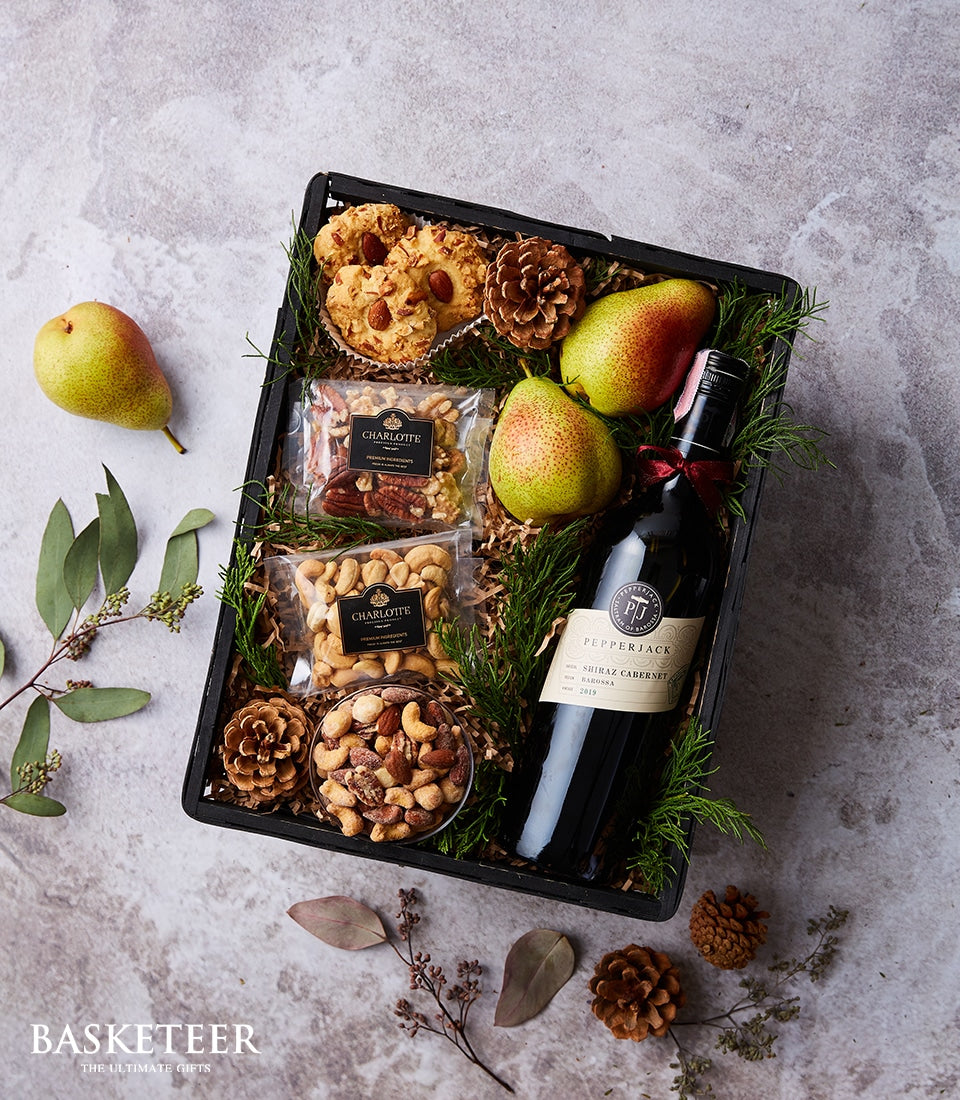 Elegant wine gift basket with Shiraz Cabernet, pears, almonds, pecans, cashews, and mixed nuts on natural shredded paper