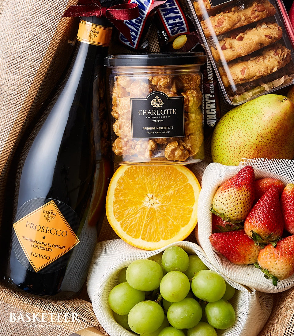 Prosecco sparkling wine with fresh fruit, caramel popcorn, and artisan cookies in luxury gift hamper