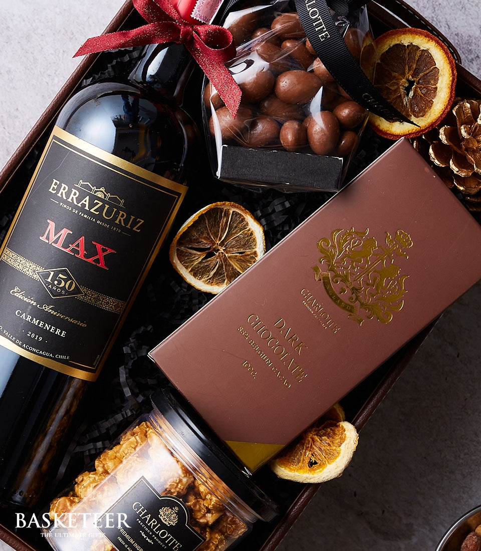 Premium wine and gourmet chocolate gift box with chocolate-covered nuts, dark chocolate bar, and caramel popcorn