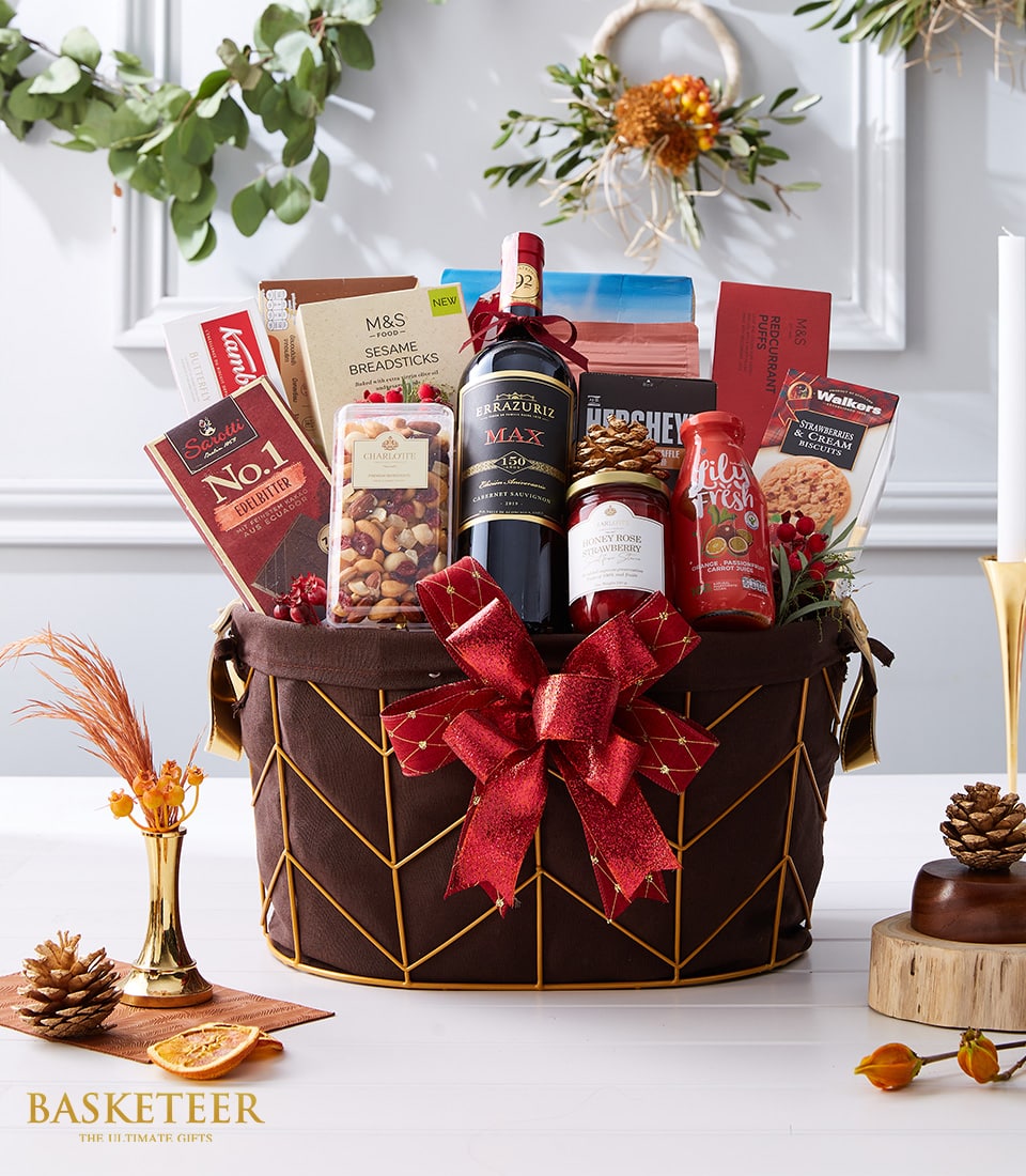 Premium red wine gourmet gift hamper with artisan crackers, jam, nuts, and holiday trimmings in gold wire basket