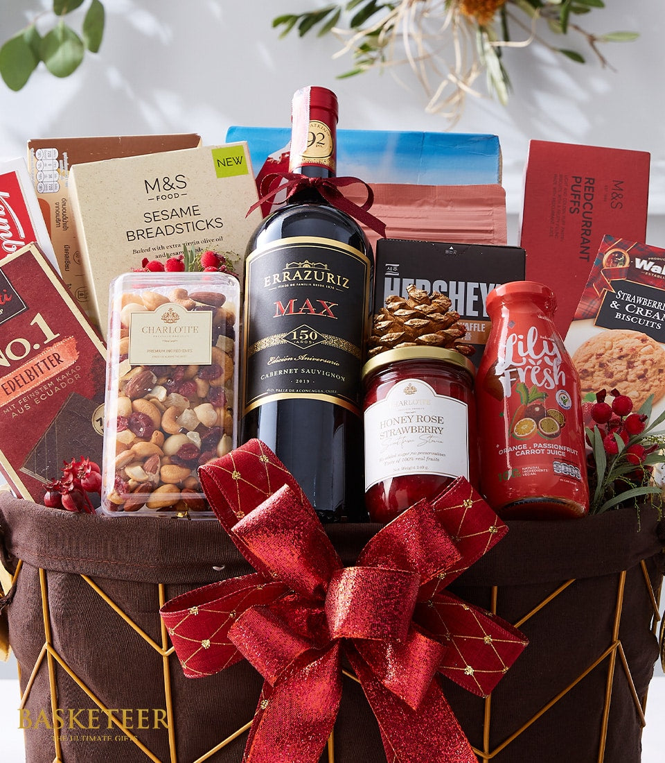 Premium wine gift hamper with gourmet crackers, nuts, chocolate and spreads in gold-trimmed basket with red ribbon