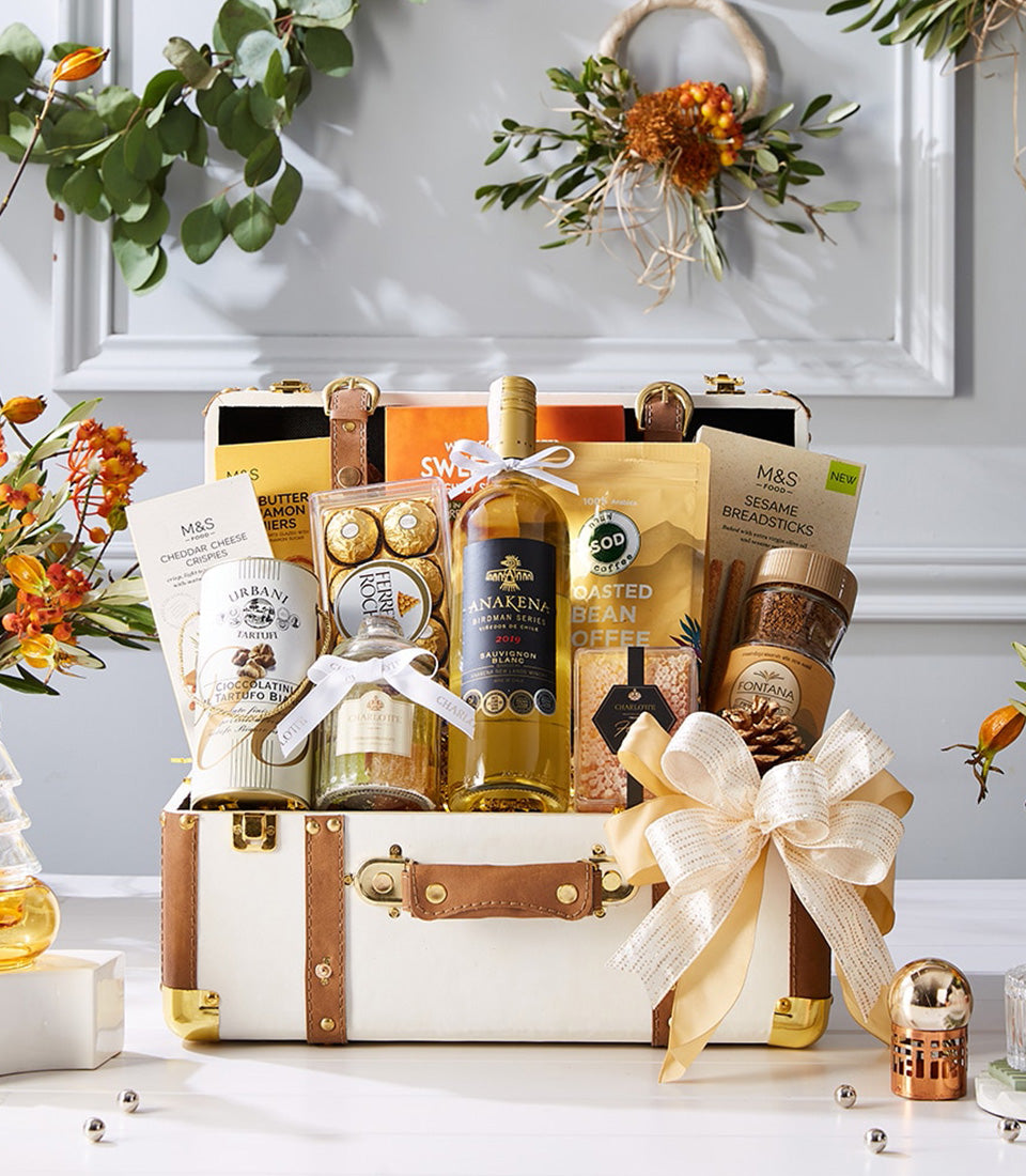Luxury white wine and gourmet hamper in cream leather trunk with chocolates, coffee, and artisan crackers
