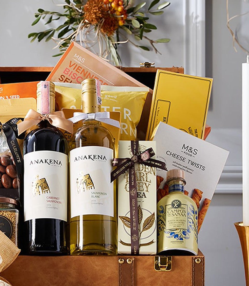 Luxury wine gift hamper with red and white wines, gourmet foods, and artisan treats in leather trunk
