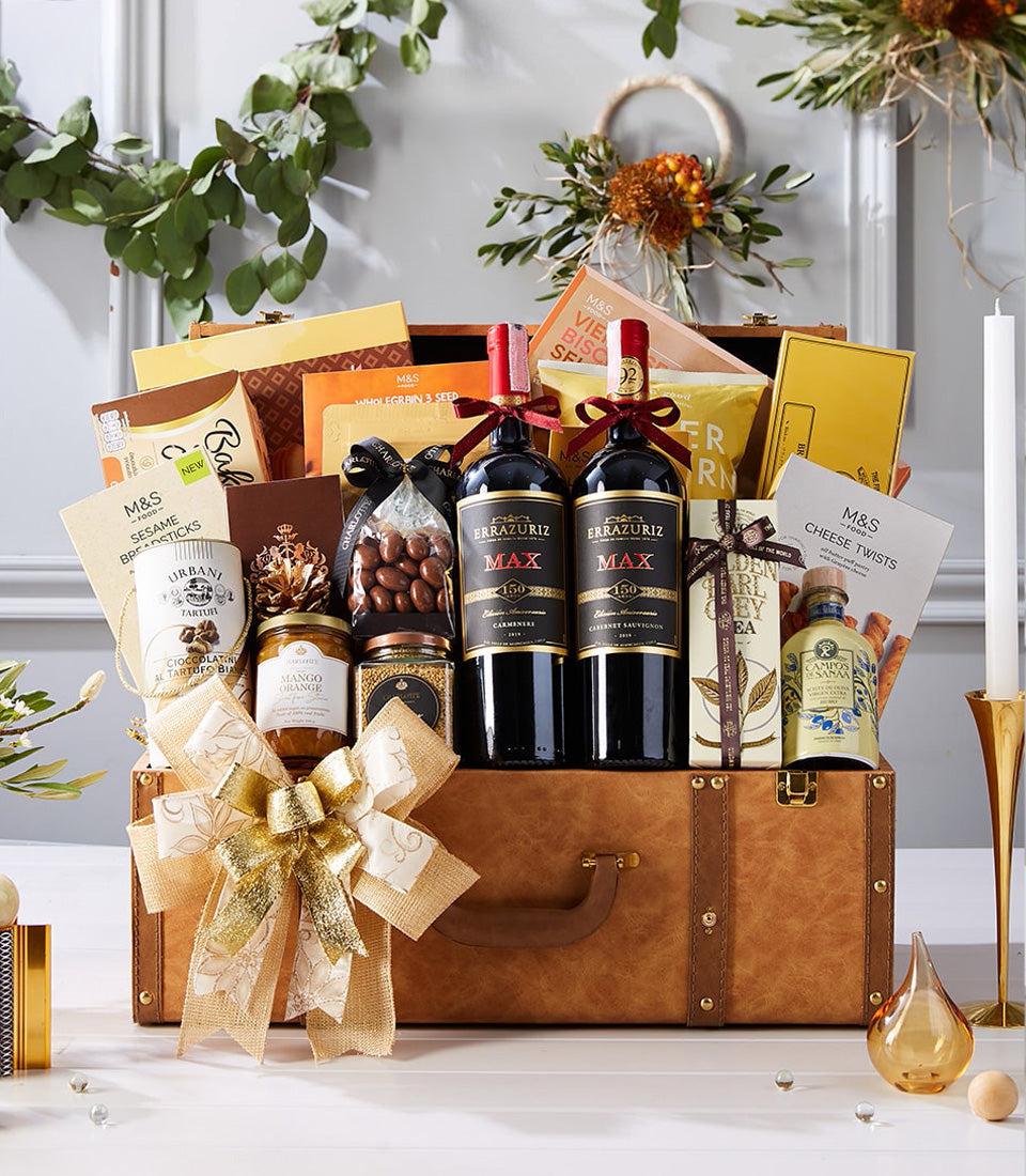Luxury brown leather suitcase hamper with dual red wines, gourmet preserves, chocolates, and festive gold ribbon bow