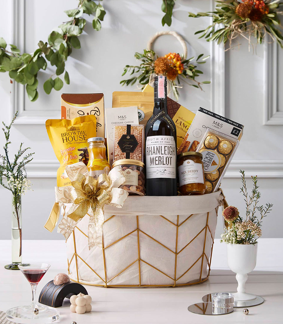 Luxe gold wire gift basket with Merlot wine, gourmet chocolates, brownies, and artisan preserves