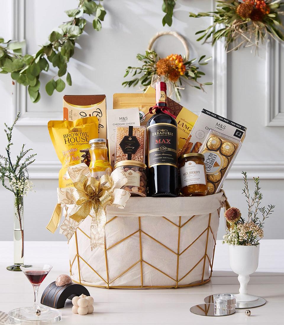 Premium red wine gift basket with gourmet chocolates, brownies, jam, and artisan snacks in gold-trimmed wire frame