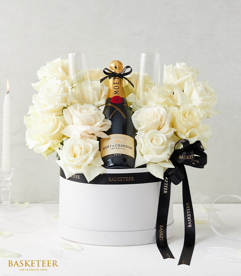 Champagne bottle with flutes and fresh white roses in luxury hatbox, premium anniversary gift set