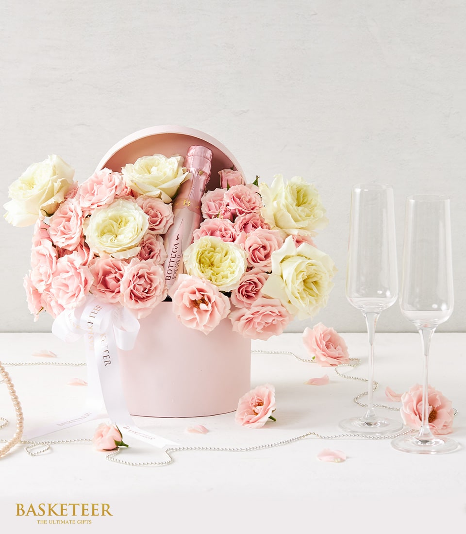 Romantic pink hatbox with Bottega Rose Gold sparkling wine, fresh roses, champagne flutes, and pearl accents for anniversary