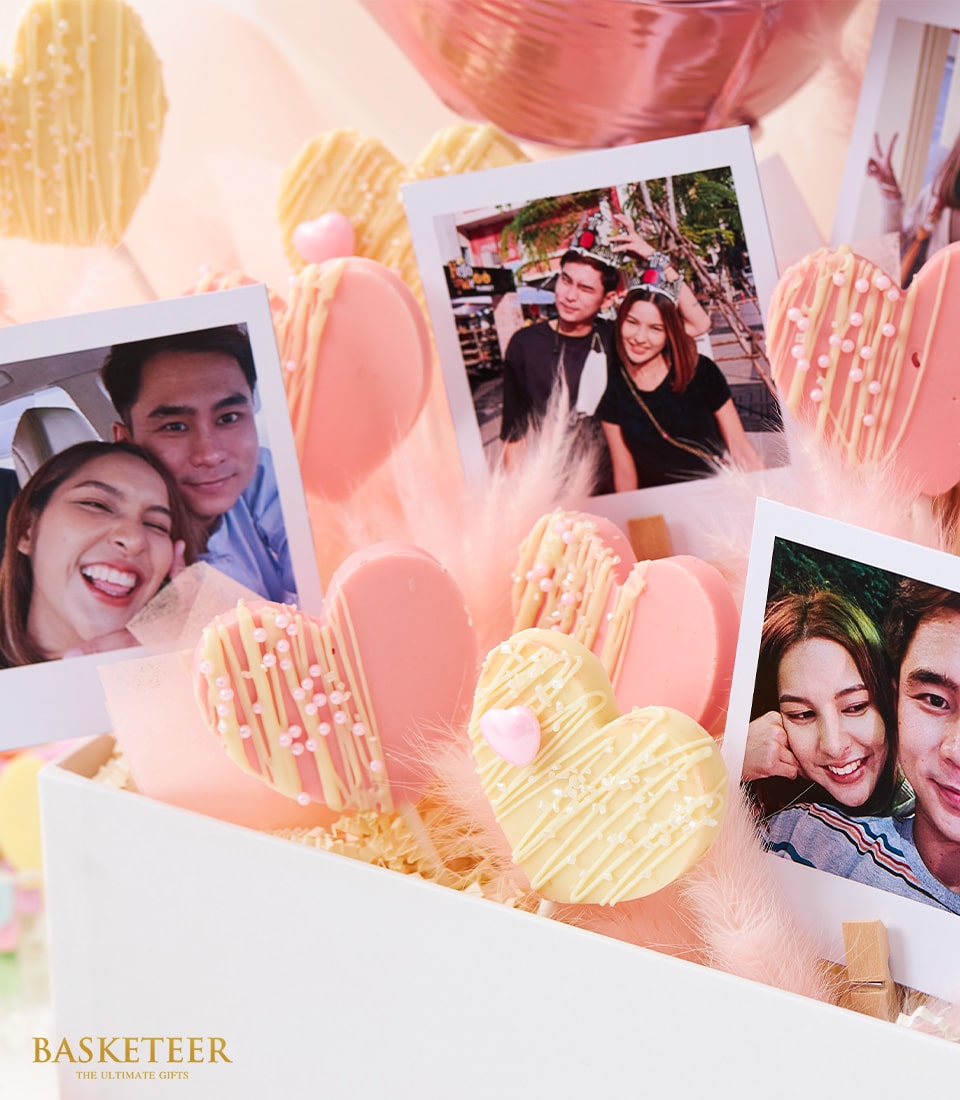Romantic rosé gift box with heart-shaped treats, couple photos, and metallic balloon for anniversaries