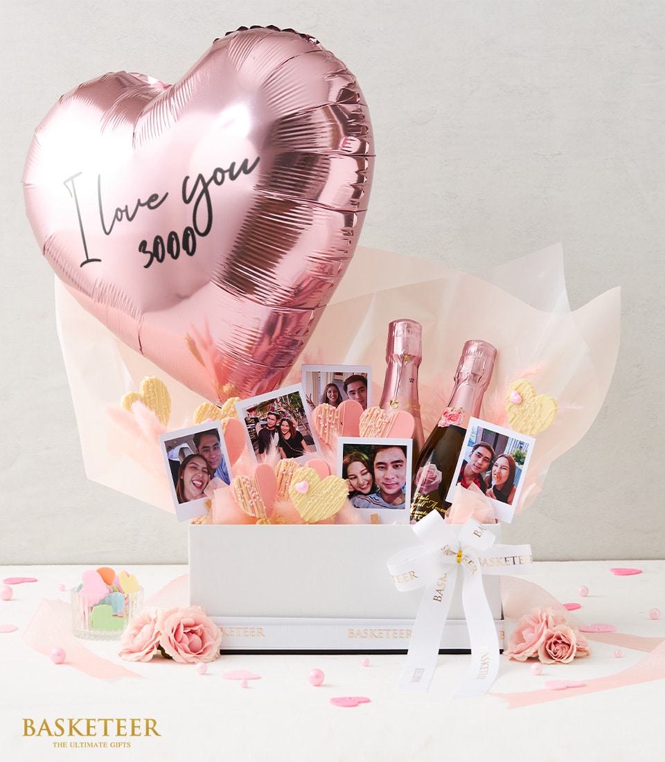 Romantic Rosé gift box with heart balloon, champagne bottles, couple photos, and pink heart chocolates for anniversaries