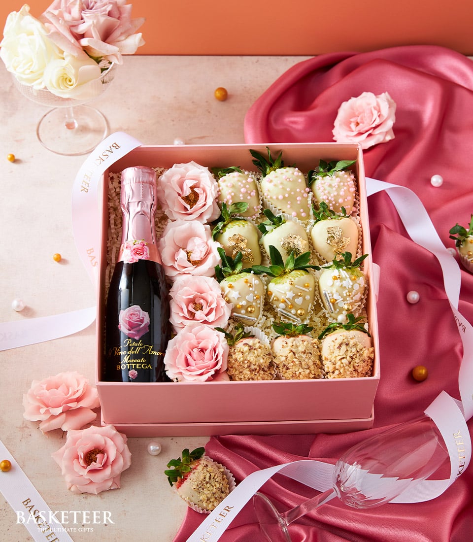 Pink gift box with sparkling wine, chocolate-dipped strawberries, and fresh roses for Valentine's Day