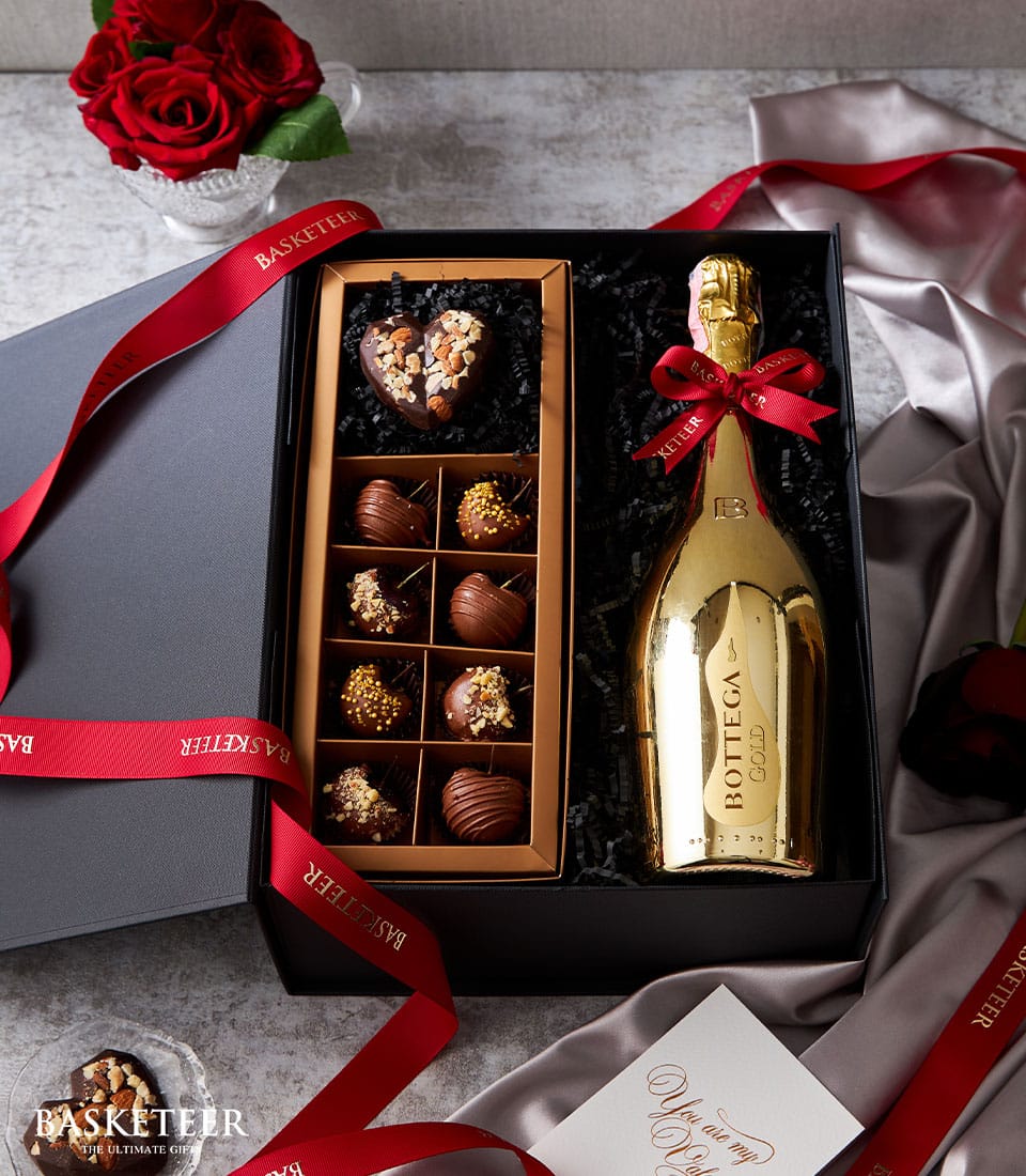 Luxury sparkling wine and gold heart-shaped chocolate gift box with red roses for Valentine's Day