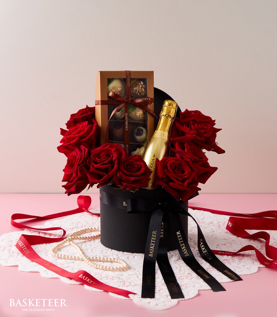 Luxury red roses, champagne, and chocolate gift box with black ribbons on white lace