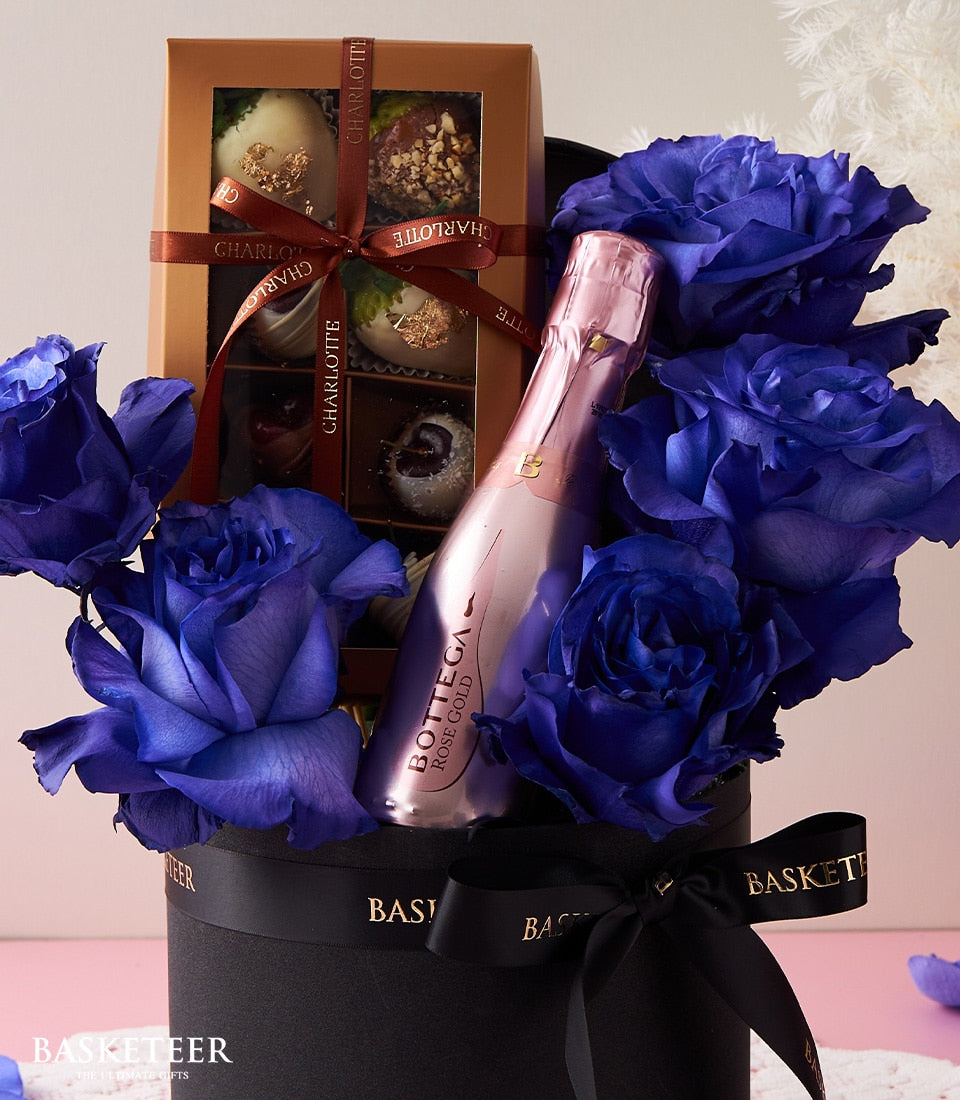 Blue roses, sparkling rosé, and Charlotte chocolates in luxury black gift box