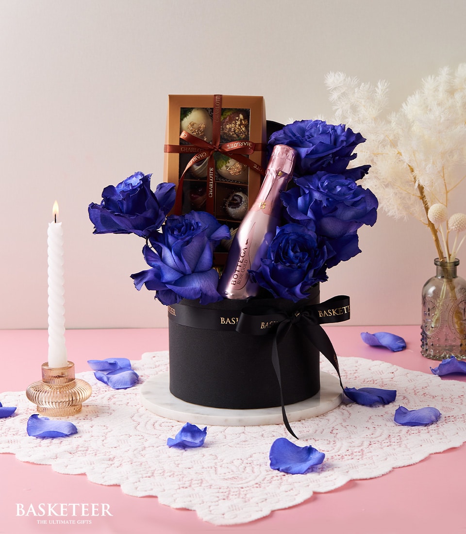 Elegant blue rose gift set with Rosé sparkling wine, chocolate-covered strawberries, and candlelight for Valentine's Day