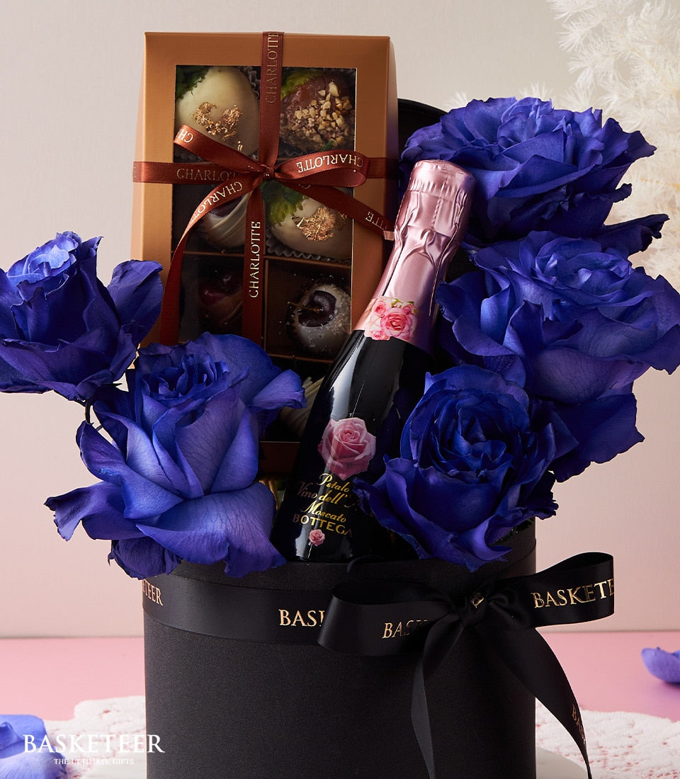 Blue roses, sparkling wine, and Charlotte chocolates in luxury black gift box for Valentine's Day