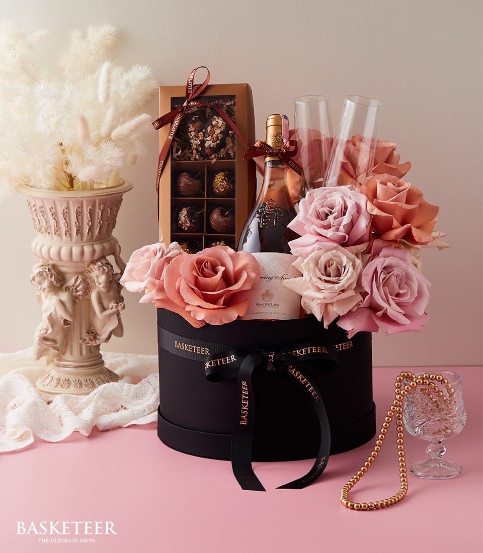 Luxury rosé wine gift box with fresh roses, champagne flutes, and chocolates for anniversaries