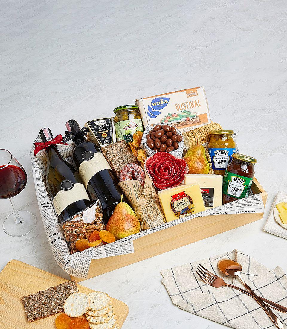 Premium wine and gourmet cheese gift basket with crackers, olives, and cured meats in wooden tray