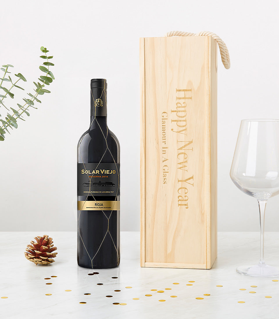 Elegant red wine gift set with engraved wooden box, wine glass, and gold festive décor