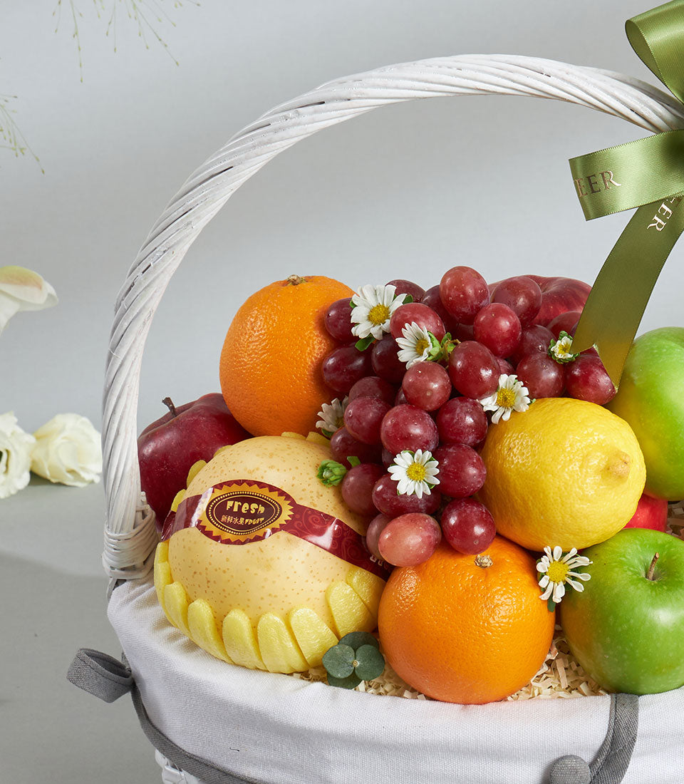 Premium fresh fruit basket with grapes, apples, pears and citrus in white wicker